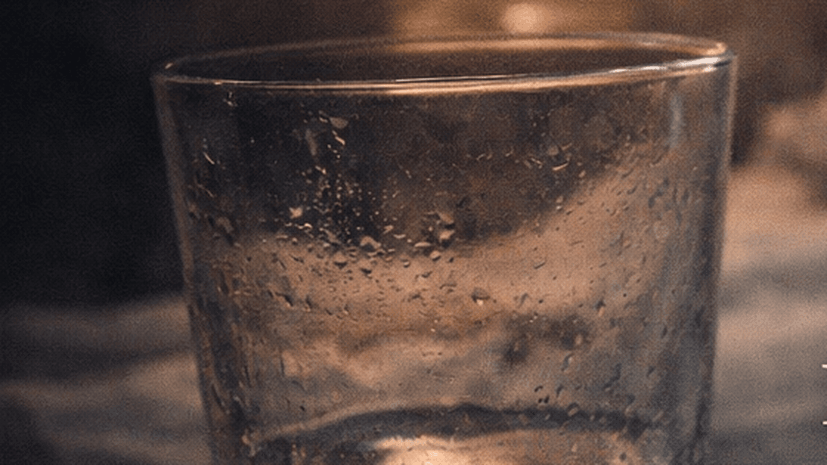 A dim bedside water glass representing nighttime dry mouth and waking for sips of water